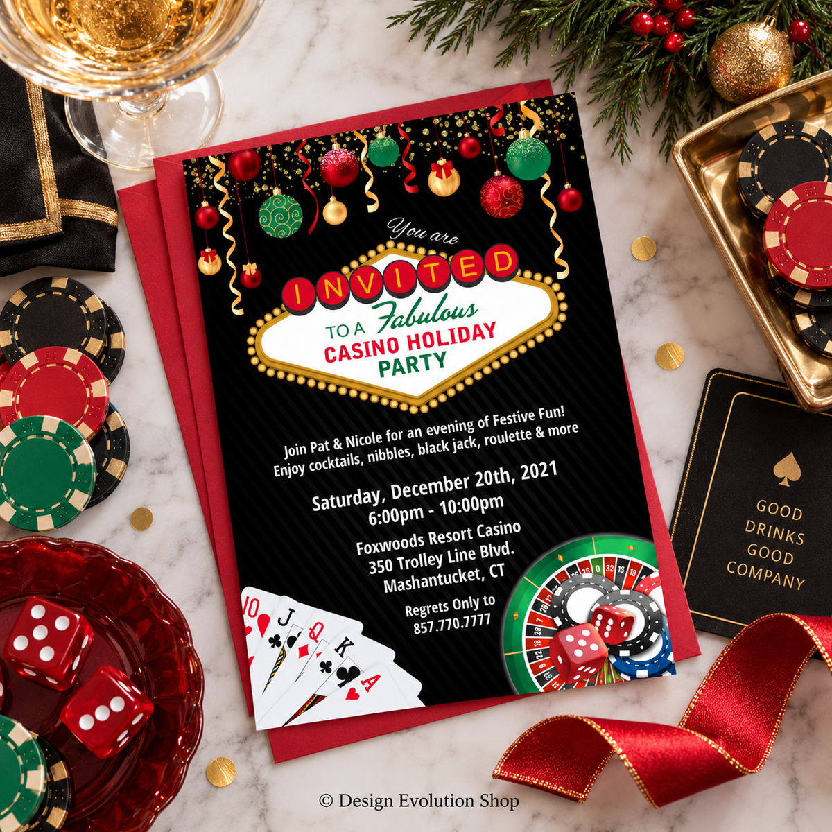 A festive casino-themed holiday party invitation card laid on a red envelope over a white marble surface, surrounded by gambling props including poker chips, dice, a drink glass, pine branches, and a gold tray.